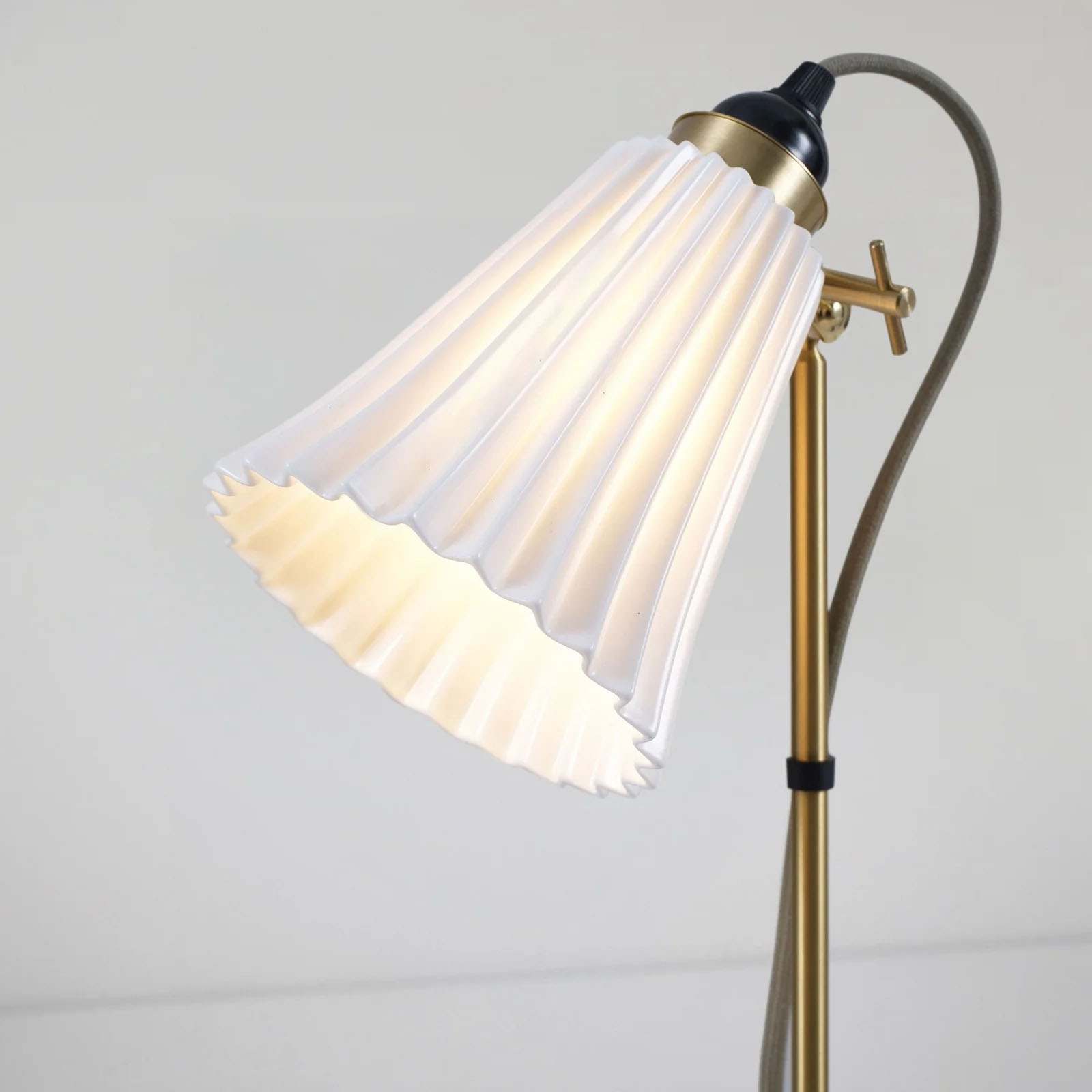 Charmante Stehlampe mit plissiertem Porzellanschirm: Die Ausführung mit Armaturen in Messing satiniert (+ grauem Baumwollkabel)