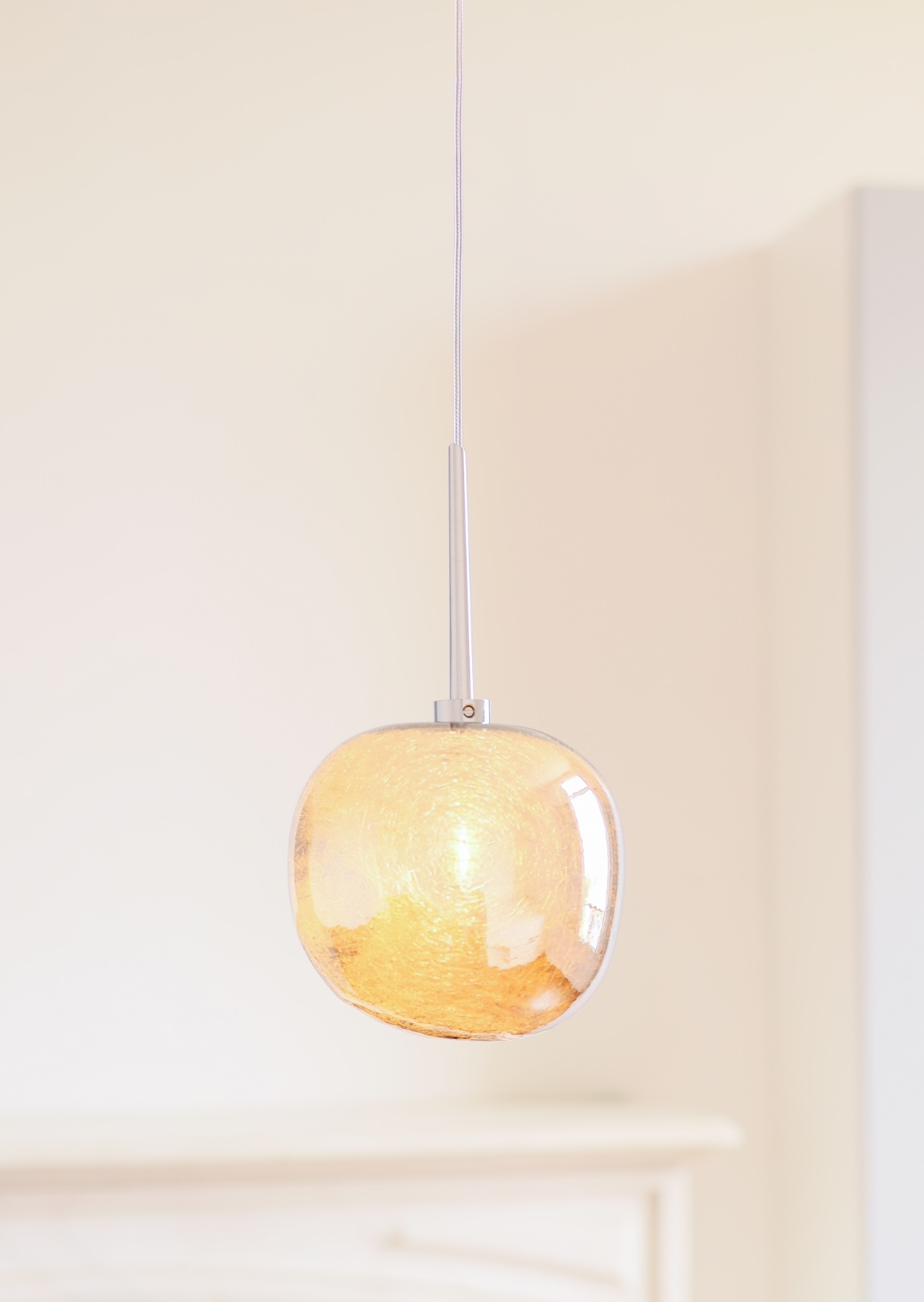 Fig. 8: Modell 2 in Gold, angeschaltet Glänzendes Silber oder Gold: Glas-Hängeleuchte GALET in drei Größen: Modell 2 in Gold, angeschaltet