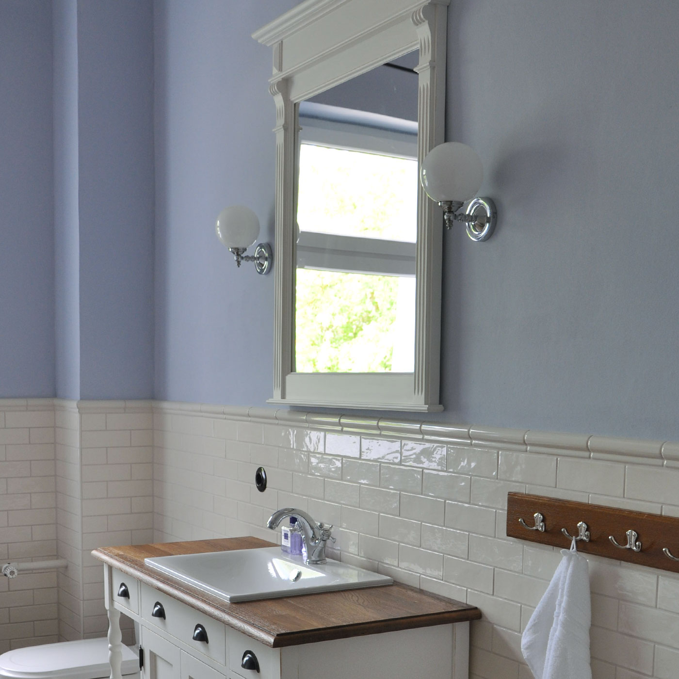 Glaskugel-Wandleuchte mit antiker Anmutung: Wandleuchte im nostalgischen Landhaus-Badezimmer neben dem Spiegel