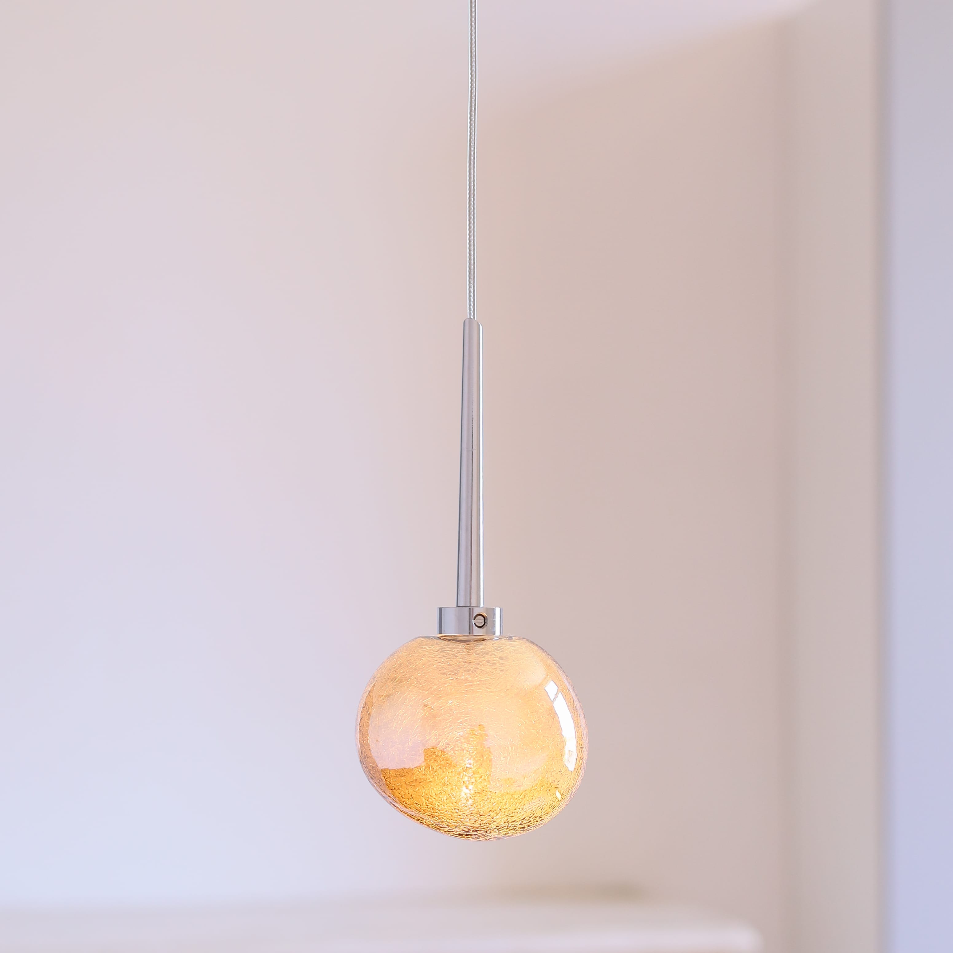 Fig. 9: Modell 1 in Gold, angeschaltet Glänzendes Silber oder Gold: Glas-Hängeleuchte GALET in drei Größen: Modell 1 in Gold, angeschaltet