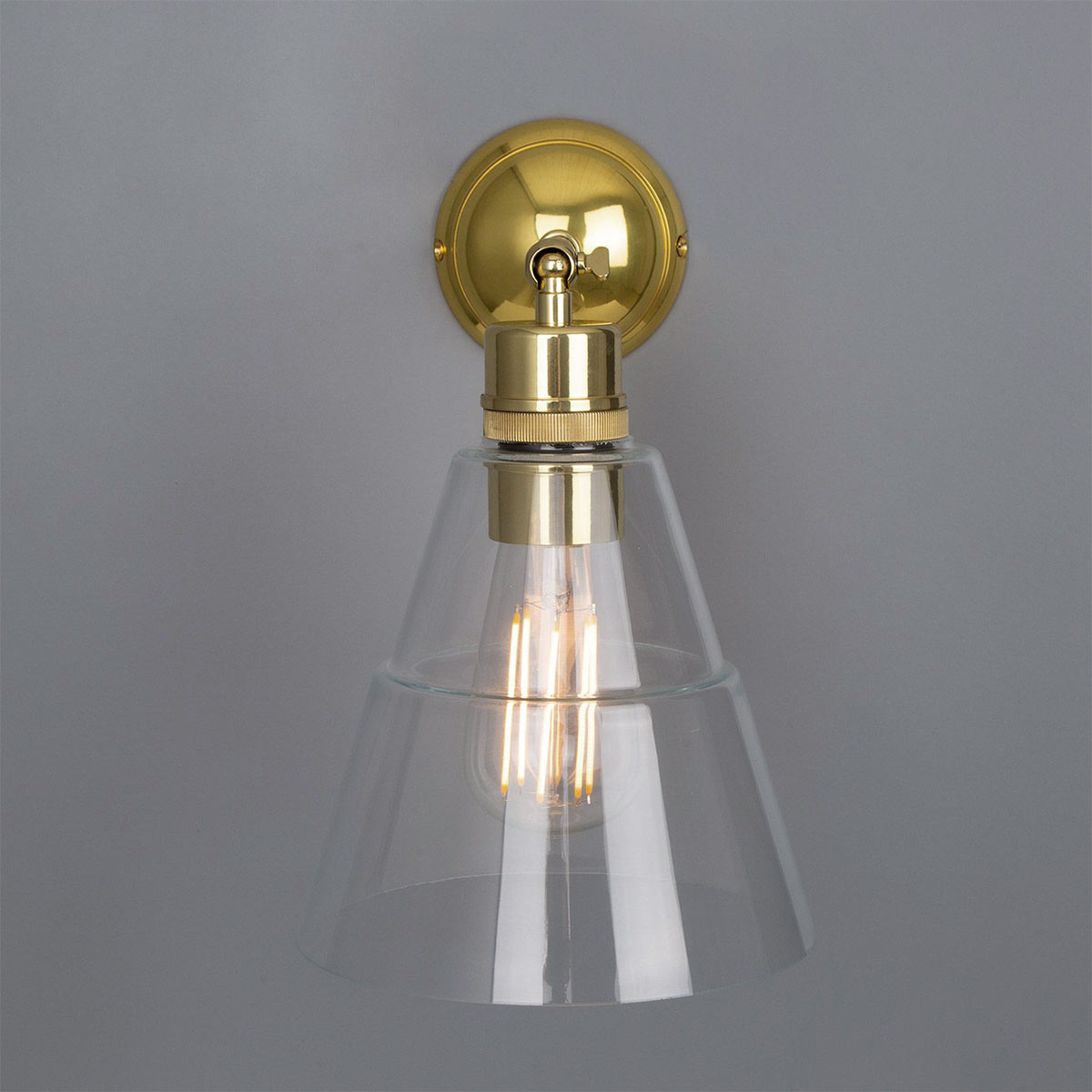 Schlichte kleine Wandleuchte mit abgestuftem Glasschirm: Die Wandlampe mit Kegal-Glasschirm, hier in Messing poliert